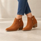 Women's block-heel ankle boots with side zip worn in a neutral studio
